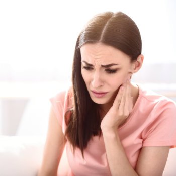 brunette with toothache touching her cheek