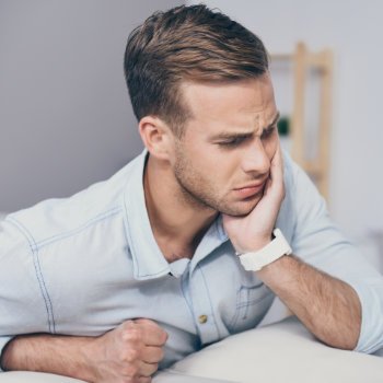 man with severe dental pain touching his cheek