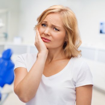 mature woman with tooth pain pressing her cheek and jaw with her hand